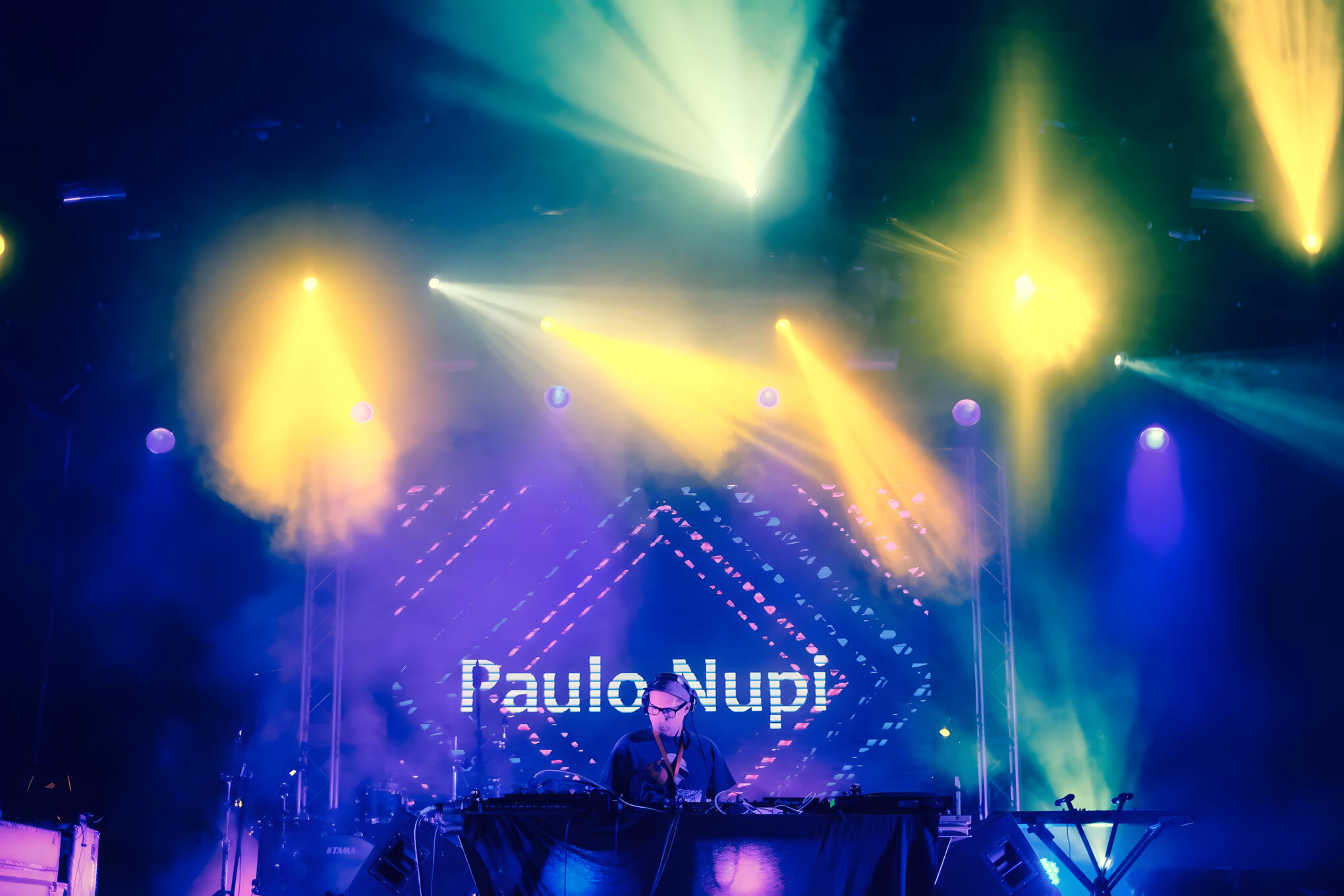 Paulo Nupi DJ set Paulo Nupi performing a live DJ set on stage with colourful lights